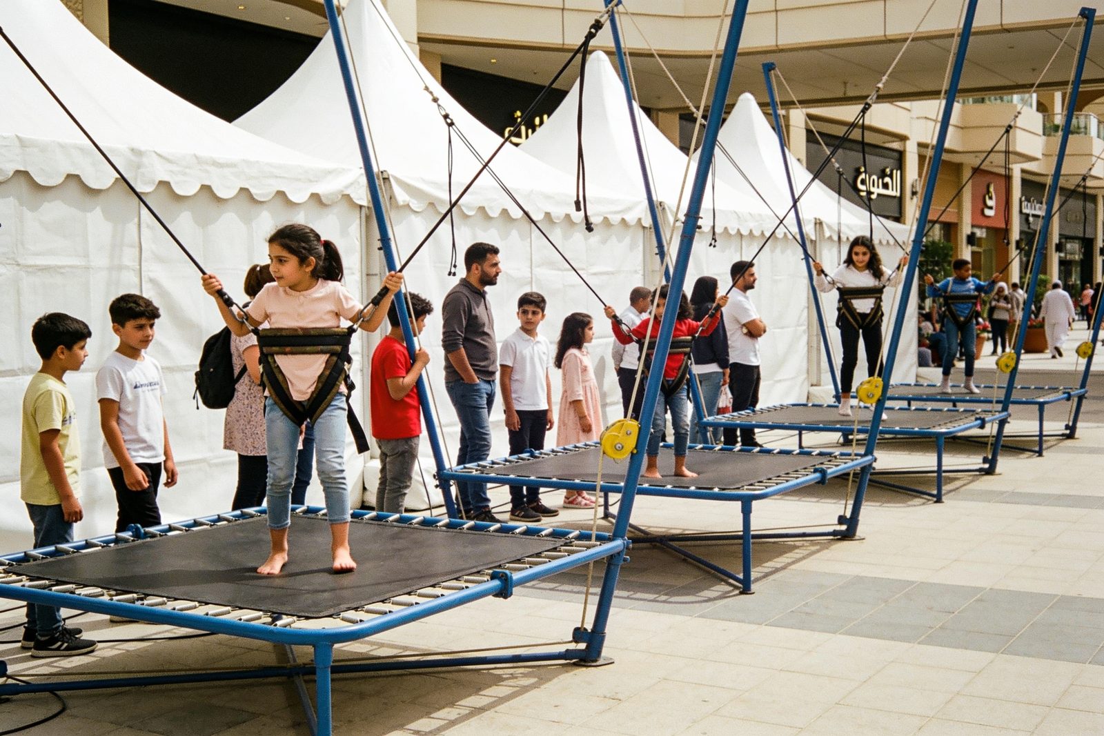 Children lining up for bungee trampolines at a Dubai event
